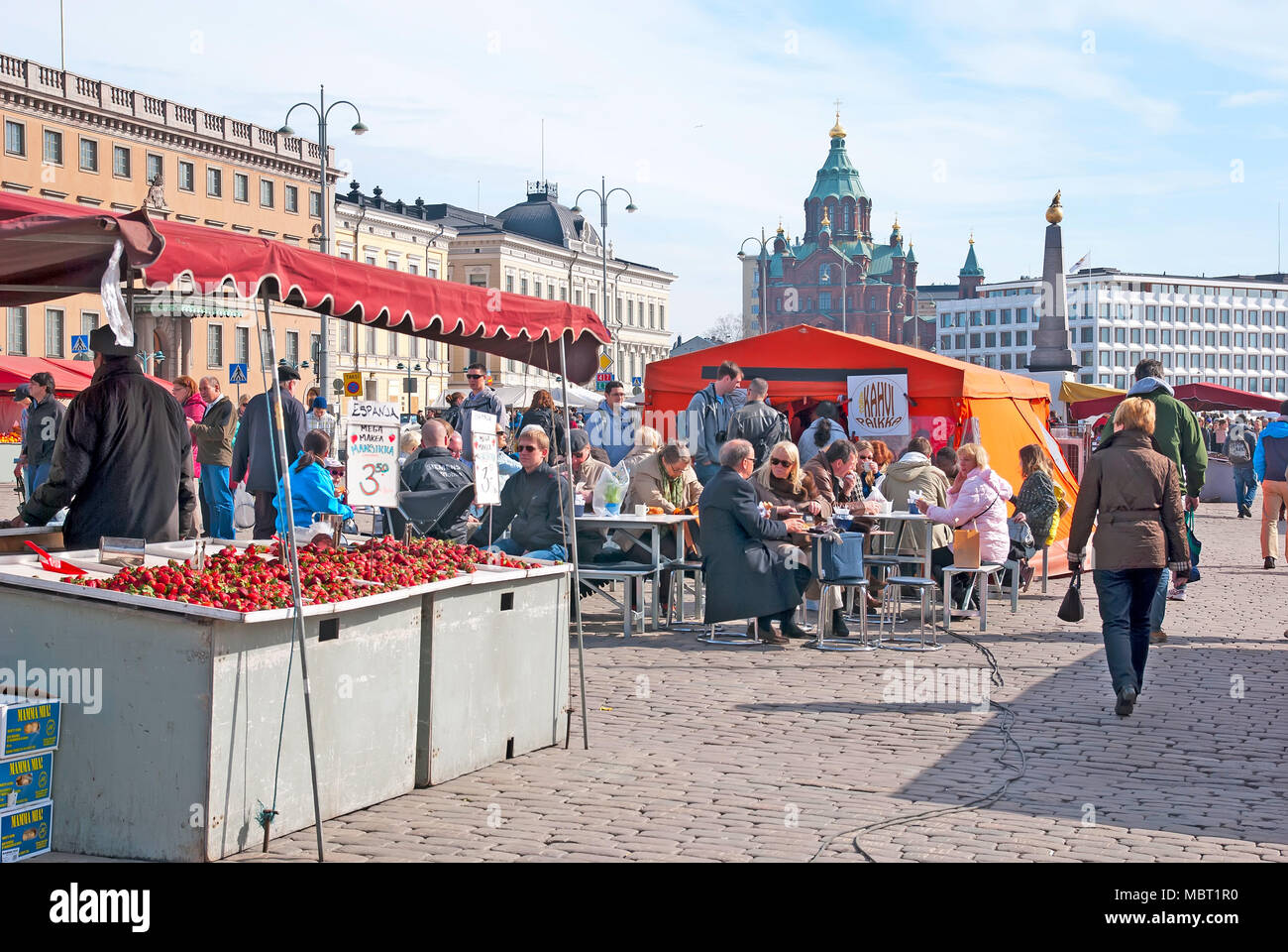 HELSINKI, FINLAND - APRIL 16, 2011:  People in the open air cafe on the Market Square near Gulf of Finland. On the background is Uspenski Cathedral Stock Photo