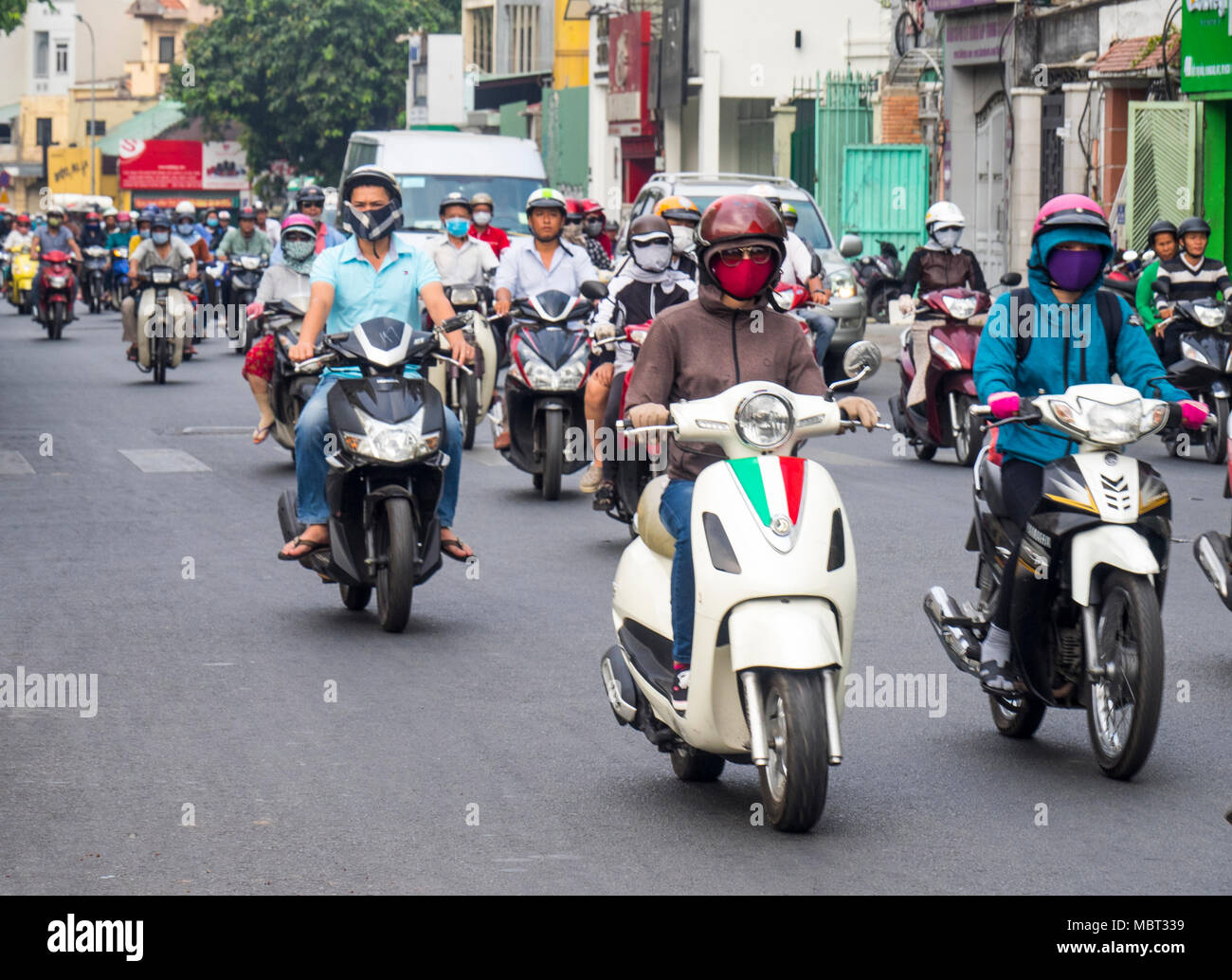 Motorcyclists, many wearing face masks, riding their motorbikes on the streets of Ho Chi Minh City, Vietnam. Stock Photo