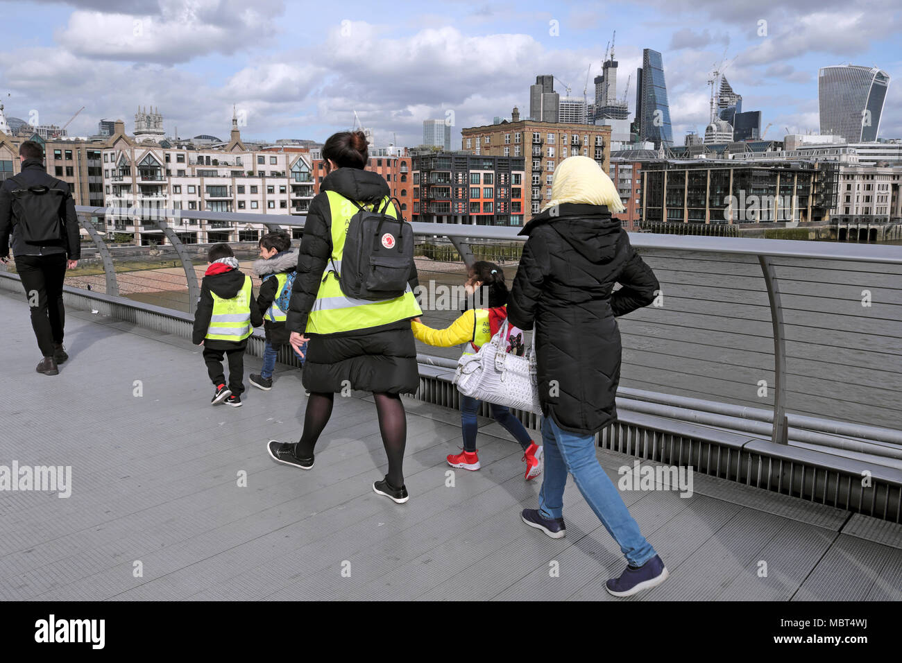 British primary schoolchildren kids walk across the Millennium Bridge holding hands with teacher in South London, England UK  KATHY DEWITT Stock Photo