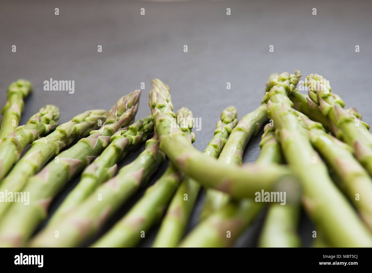 Raw ingredients: spears of asparagus on a slate board, shallow depth of field Stock Photo