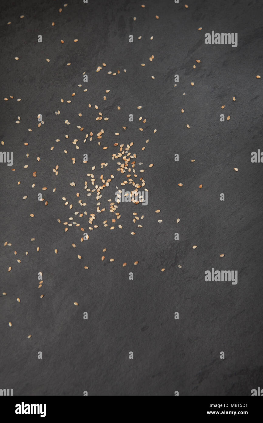 Raw ingredients: sesame seeds scattered across a slate board, flat lay Stock Photo