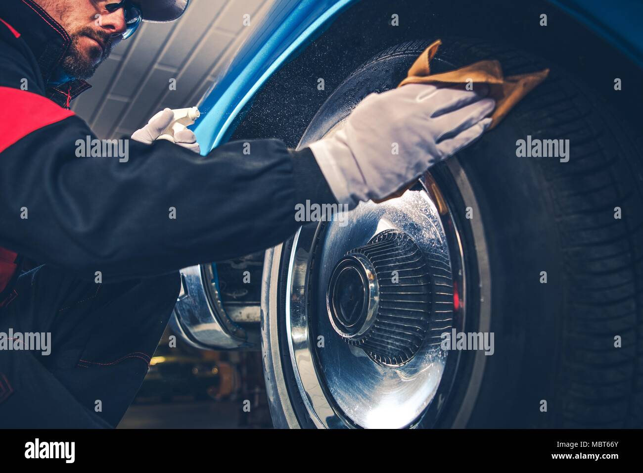 Caucasian Collector Taking Care of His American Classic Car. Chromed Wheels Cleaning. Stock Photo