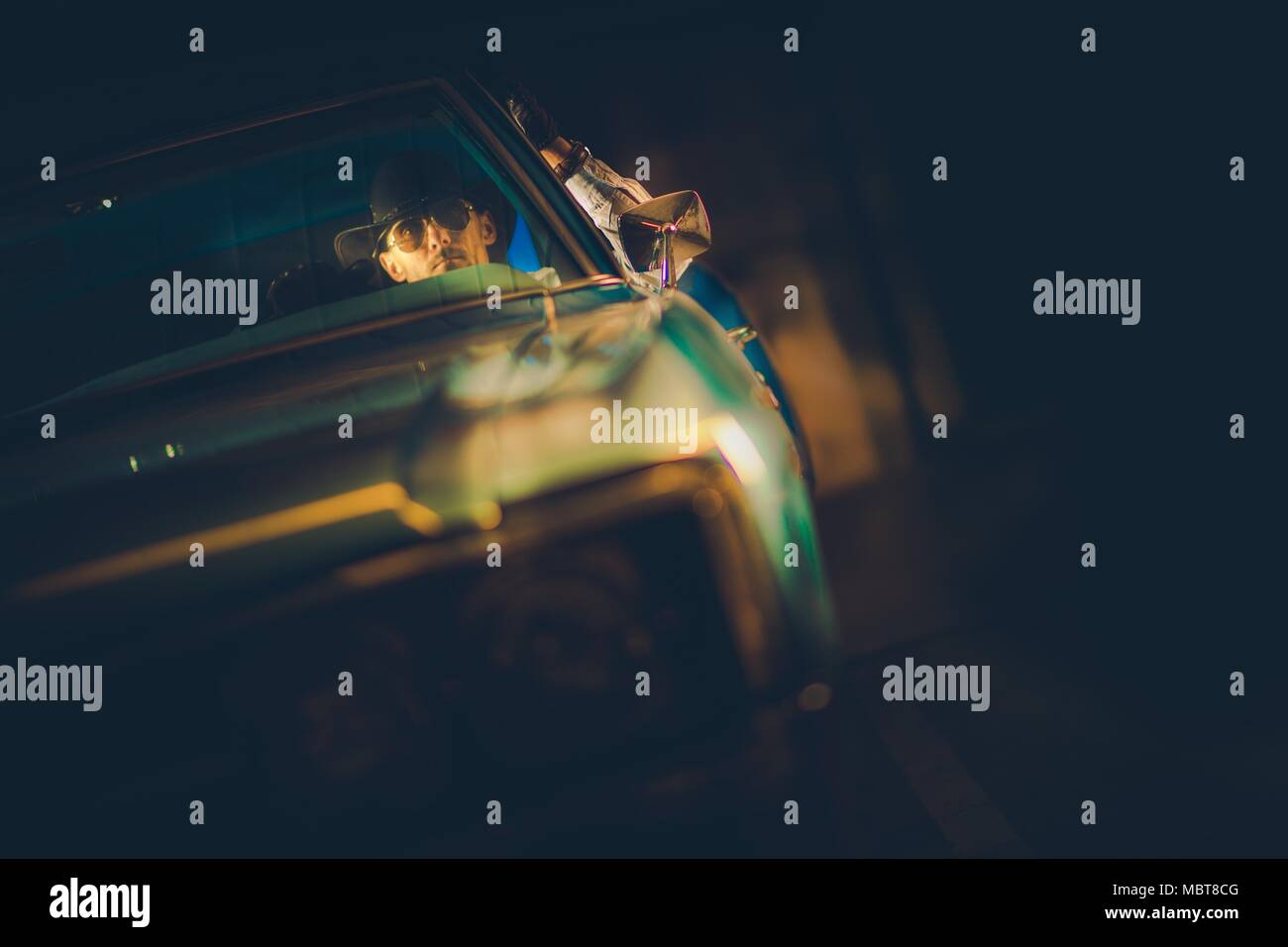 Caucasian Cowboy in His 30s and His American Muscle Car Ride in the Dark. American Transportation. Stock Photo