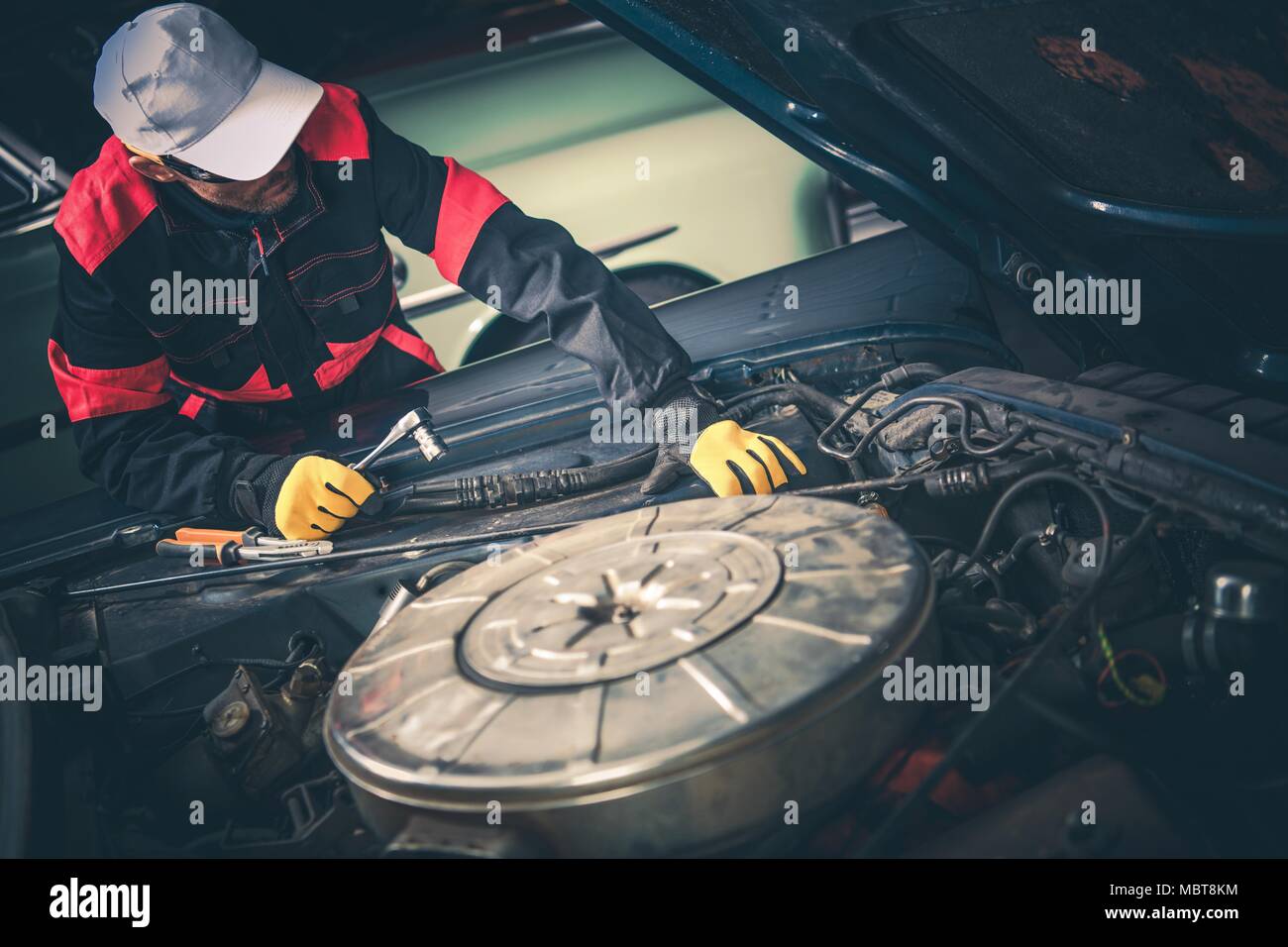 Vintage Car Mechanic Trying to Fix Classic Car. Huge Big Block Engine Restoration. Stock Photo