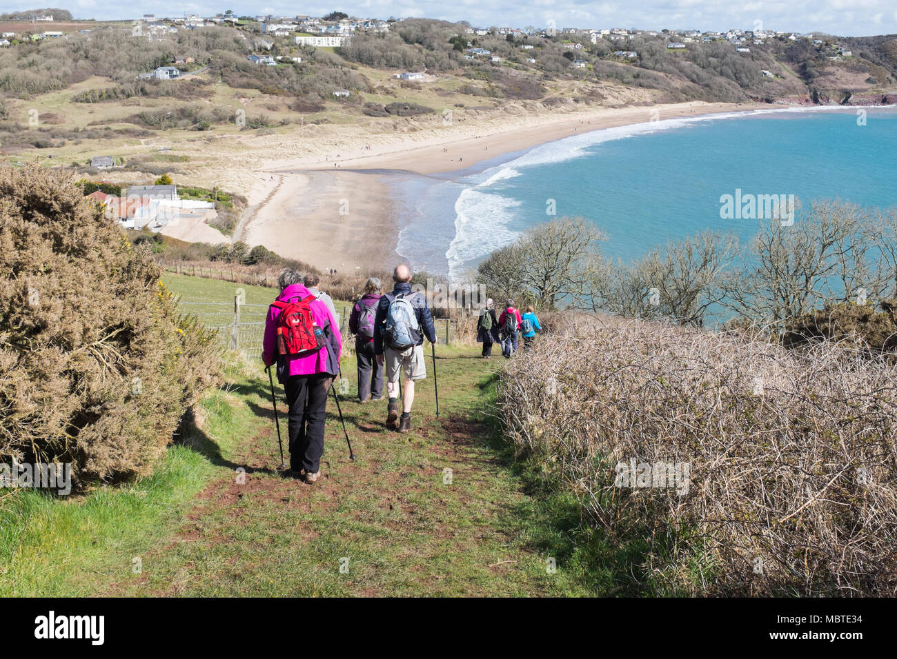 Group of walkers or ramblers descending a hill on the Pembrokeshire Coastal Path towards Freshwater East Stock Photo