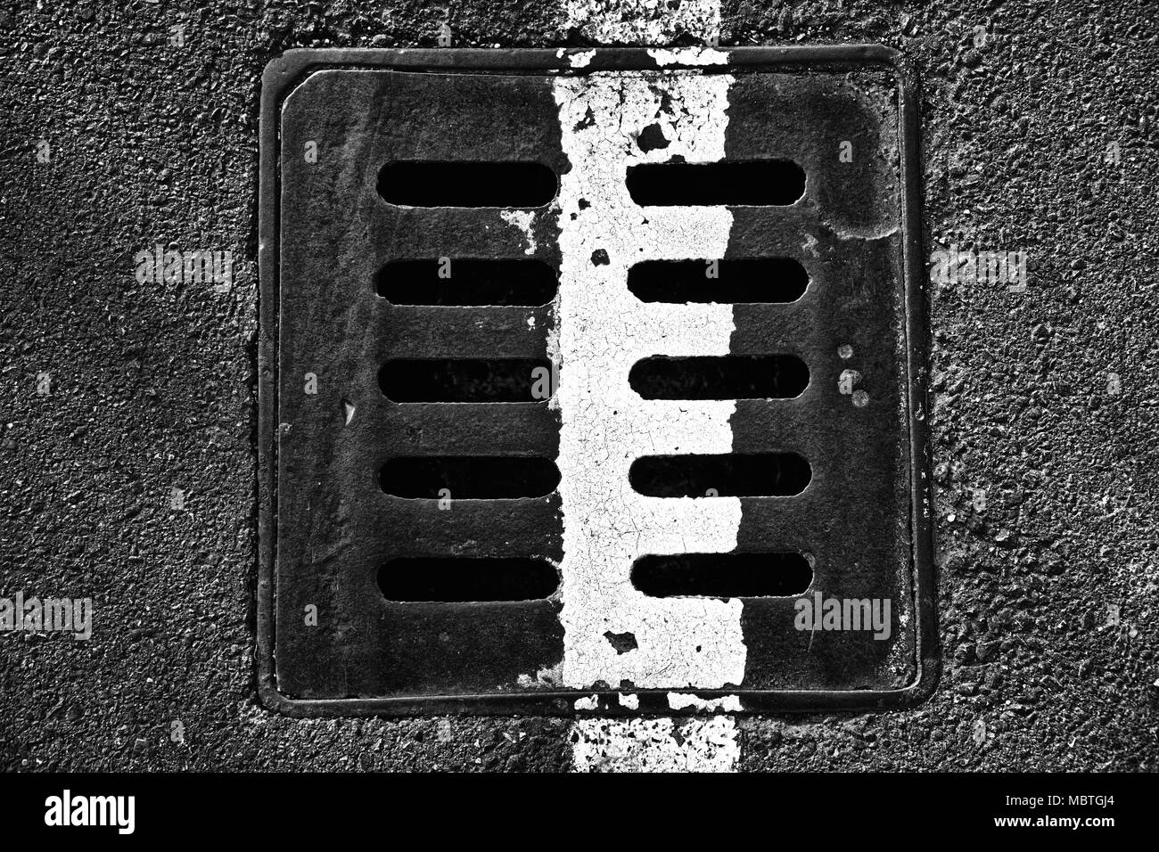 Square metal hatch in urban pavement, sewer manhole cover with marking lines. Stock Photo