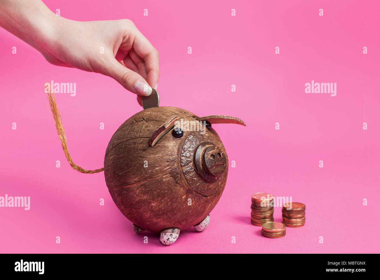 Women hand puts coin in a piggy bank isolated on pink background Stock ...