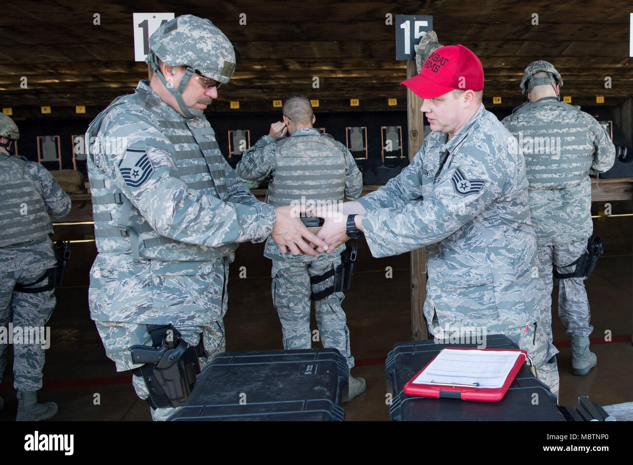 U.S. Air Force Staff Sgt. Corey Wilson, a Combat Arms Training and Maintenance Instructor with the 130th Security Forces Squadron, hands U.S. Air Force Master Sgt. Paul Ruddle ammunition for an M4 rifle Jan. 10, 2018 at the Combat Arms Training and Maintenance Facility for the Combat Readiness Training Center, Gulfport, Miss. Airmen must be weapon qualified every 18 months to ensure mission readiness. Stock Photo