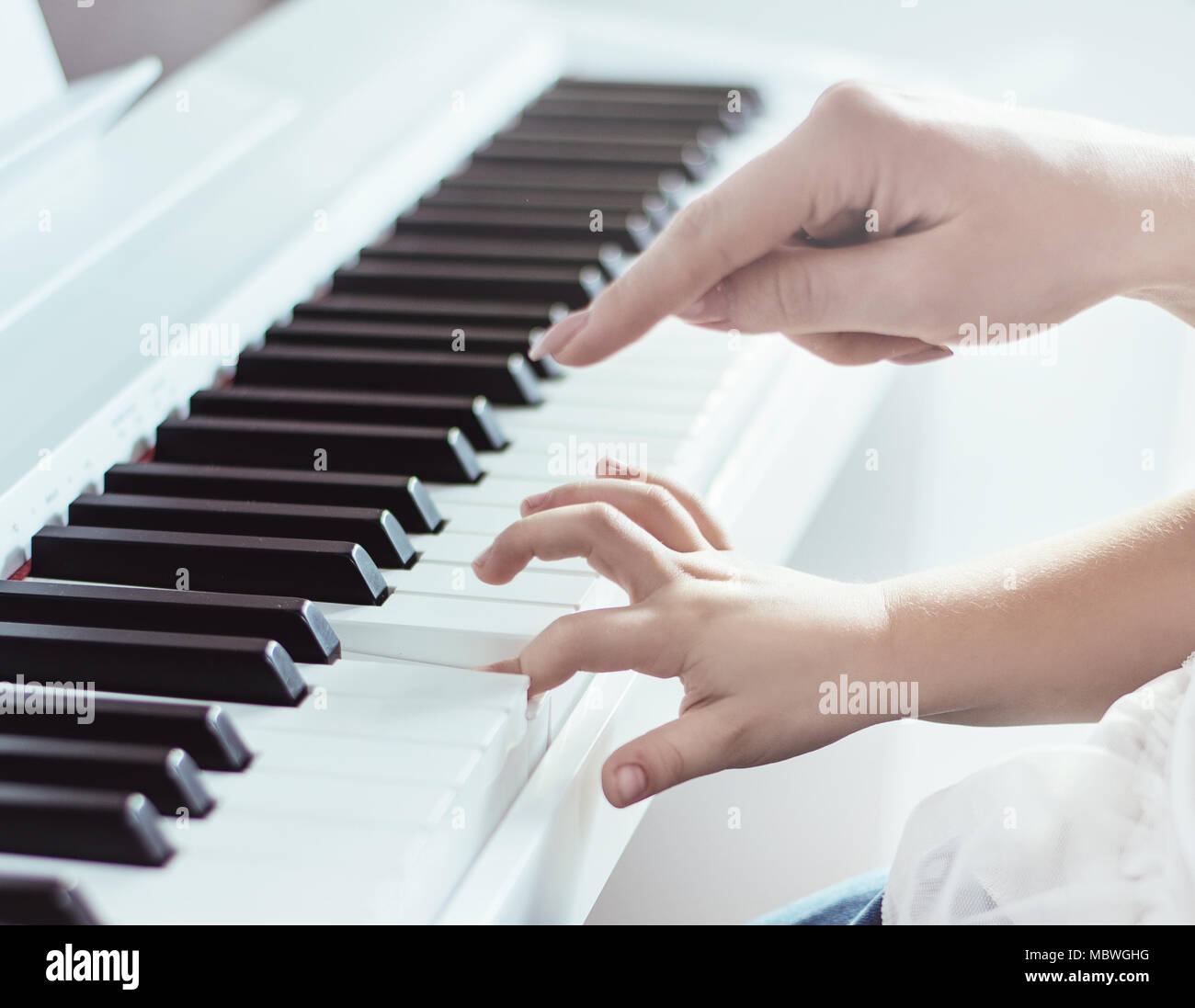 Closeup picture of two hands of mother and daughter playing piano Stock Photo