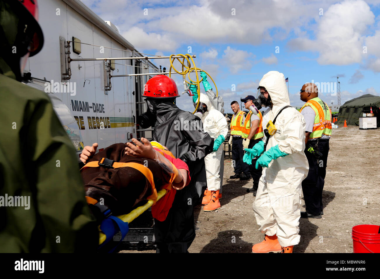 Soldiers assigned to the 414th Chemical Company from Orangeburg, South Carolina and members of the Miami-Dade Fire Department Hazmat team work together to decontaminate a simulated casualty during a Joint Training Exercise hosted by the Homestead-Miami Speedway and Miami-Dade Fire Department in Miami, Florida. Jan. 11, 2018. This JTE focused on building response capabilities and the seamless transition between the local first responders and the follow-on support provided by the National Guard and Active duty soldiers. (U. S. Army Photo by Spc. Samuel Brooks) Stock Photo