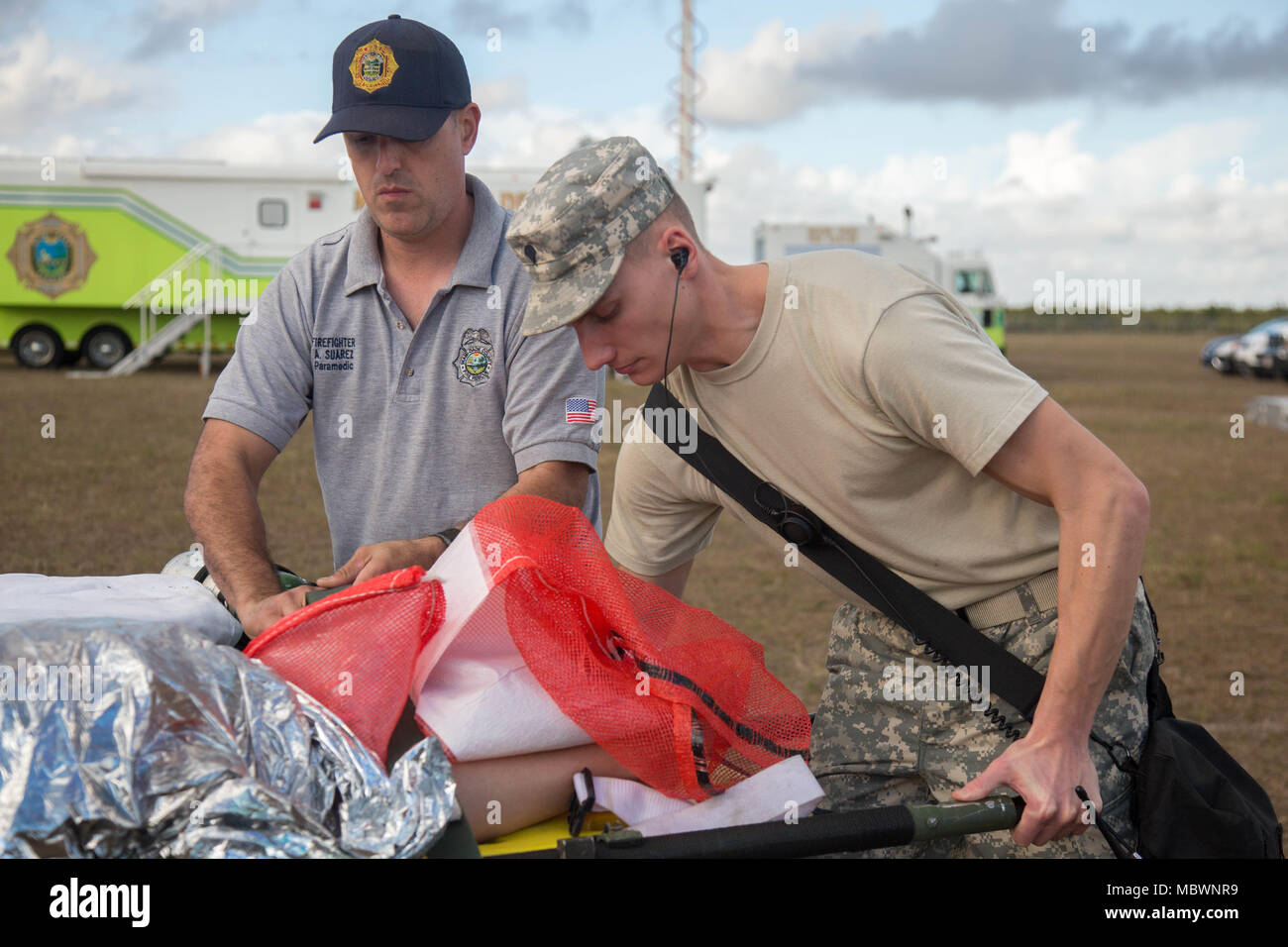 U.S. Army reserve soldier and Miami-Dade Fire Department Hazmat member, secures a casualty to a gurny for a simulated mass chemical attack during a Joint Training Exercise hosted by the Miami-Dade Fire Department and Homestead-Miami Speedway in Miami, Fla. Jan. 11, 2018. This JTE focused on building response capabilities and seamless the transition between the local first responders and the follow-on support provided by the National Guard and Active duty soldiers. (U. S. Army Photo by Spc. P.J. Siquig) Stock Photo