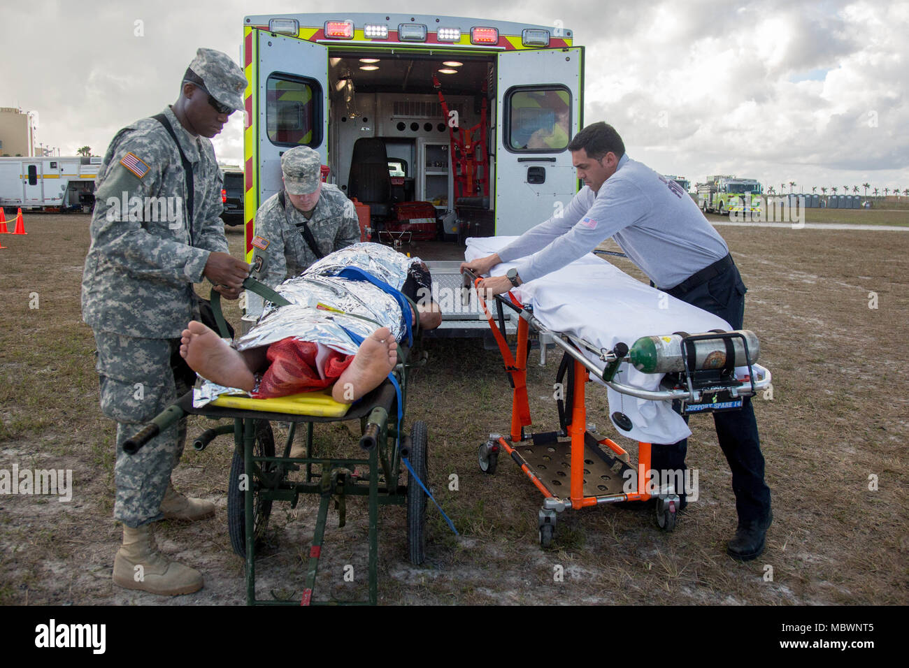U.S. Army reserve soldiers and Miami-Dade Fire Department Hazmat member, secures a casualty to a gurny for a simulated mass chemical attack during a Joint Training Exercise hosted by the Miami-Dade Fire Department and Homestead-Miami Speedway in Miami, Fla. Jan. 11, 2018. This JTE focused on building response capabilities and seamless the transition between the local first responders and the follow-on support provided by the National Guard and Active duty soldiers. (U. S. Army Photo by Spc. P.J. Siquig) Stock Photo