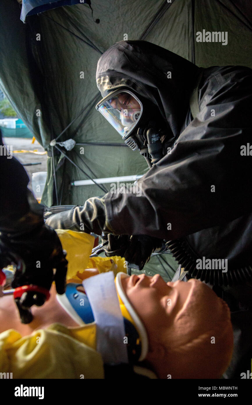U.S. Army Soldier of the 414th Chemical Company, cuts the clothing for a simulated mass chemical attack during a Joint Training Exercise hosted by the Miami-Dade Fire Department and Homestead-Miami Speedway in Miami, Fla. Jan. 11, 2018. This JTE focused on building response capabilities and seamless the transition between the local first responders and the follow-on support provided by the National Guard and Active duty soldiers. (U. S. Army Photo by Spc. P.J. Siquig) Stock Photo