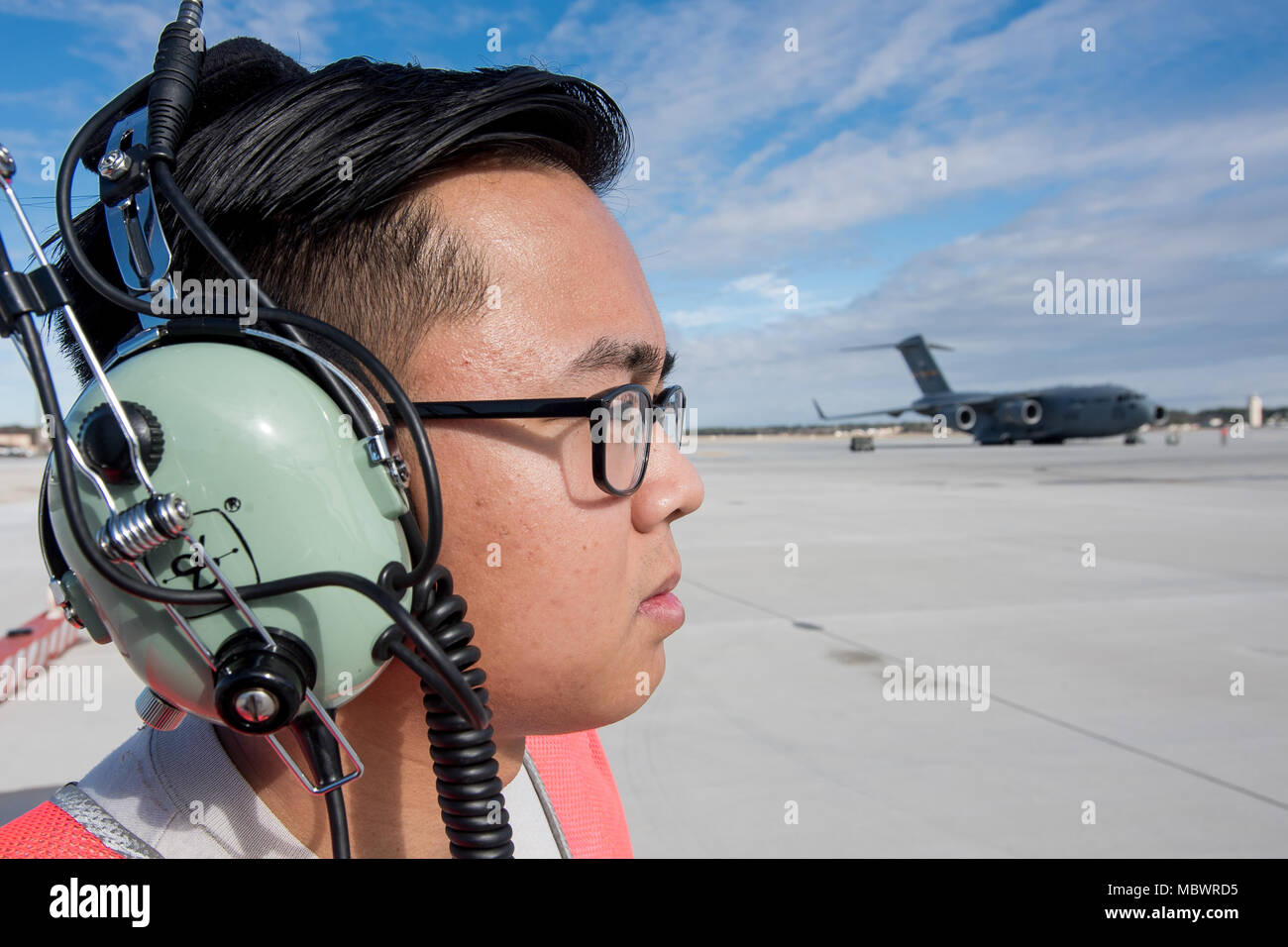 POPE ARMY AIRFIELD, N.C. — Senior Airman Mycojeb Quiocho, a crew chief in the 43d Air Mobility Squadron here, looks on as a C-130H Hercules from Georgia Air National Guard's 165th Airlift Wing prepares to launch with a load of Army paratroopers from Fort Bragg's 27th Engineer Battalion (Airborne) during joint airdrop training on Green Ramp here Jan. 10, 2018. Airmen in the 43d AMS and 43d Air Base Squadron here supported both visiting aircrews and Army units throughout the training. The 43d Air Mobility Operations Group, which is part of Air Mobility Command, powers airlift training and real-w Stock Photo