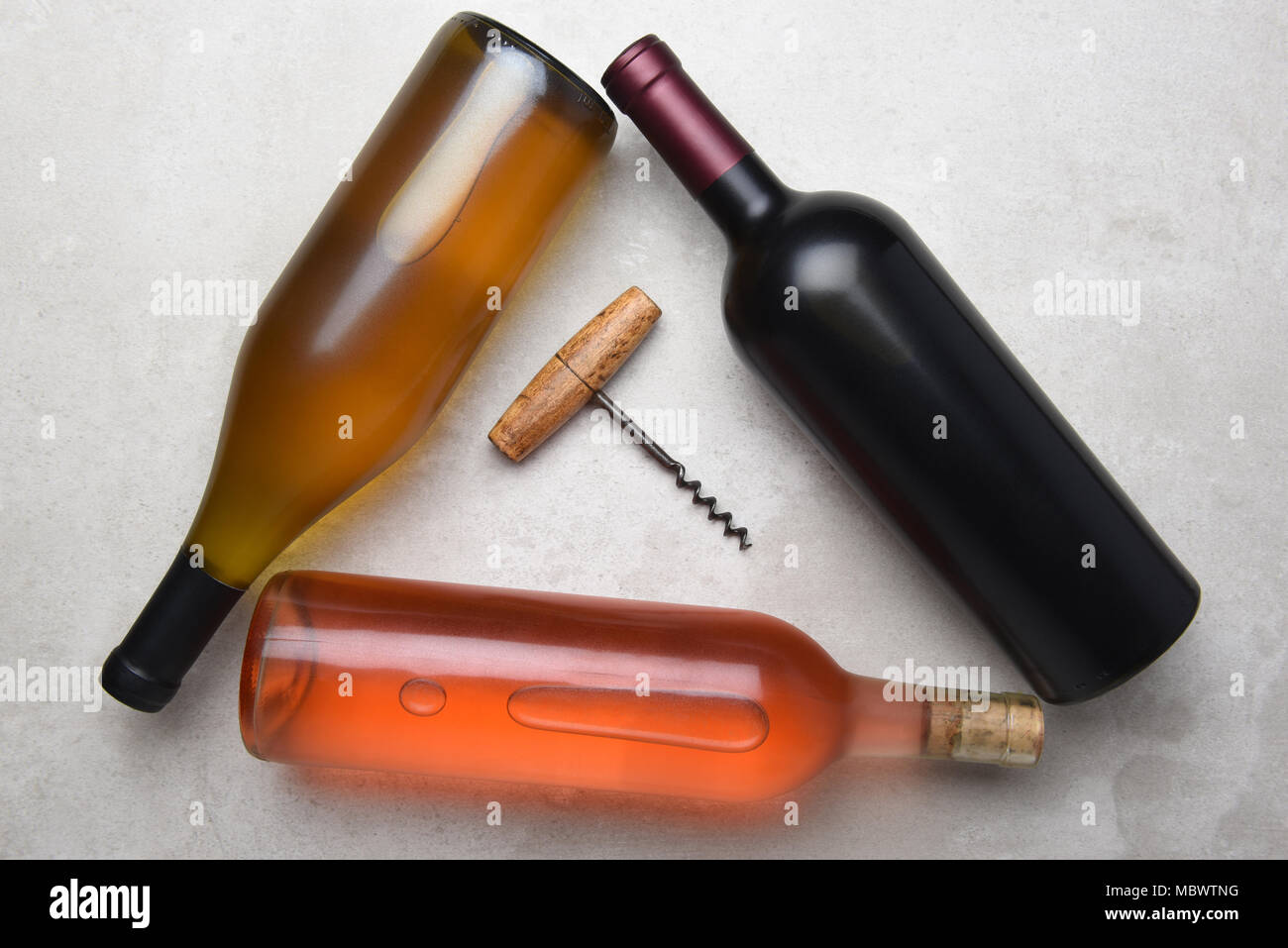 Cabernet, Rose, Chardonnay: Overhead view of a group of three different bottles arranged in a triangle with a corkcscrew in the middle. Stock Photo