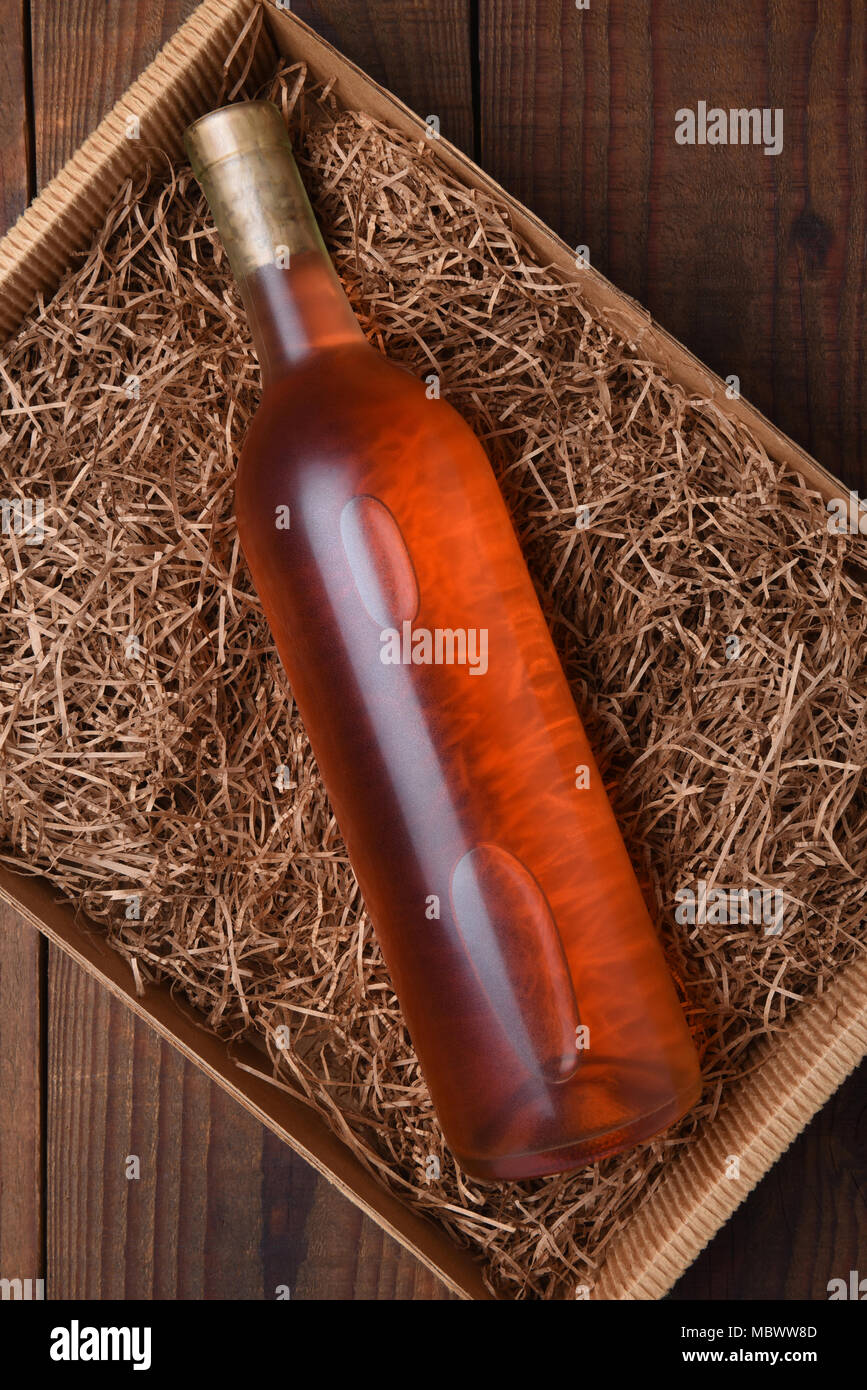 Blush Wine Bottle in Packing Straw: High angle shot of a single bottle in a cardboard box with straw packing. Stock Photo