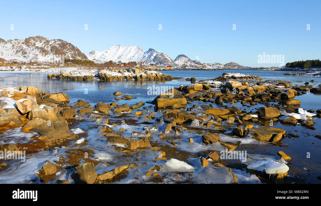 panoramic view of fjord in low tide in winter with mountains in backgrond and beautiful stones and ice in foreground , lofoten islands, norway Stock Photo