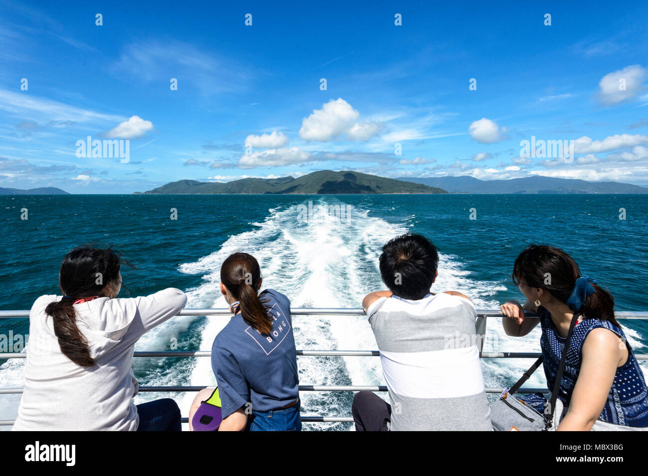 Chinese tourists looking back at the boat wake while cruising at the Great Barrier Reef, Far North Queensland, QLD, FNQ, Australia Stock Photo
