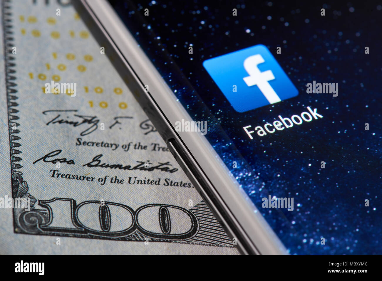 New york, USA - April 11, 2018: Facebook icon app on smartphone close-up on dollar currency background Stock Photo