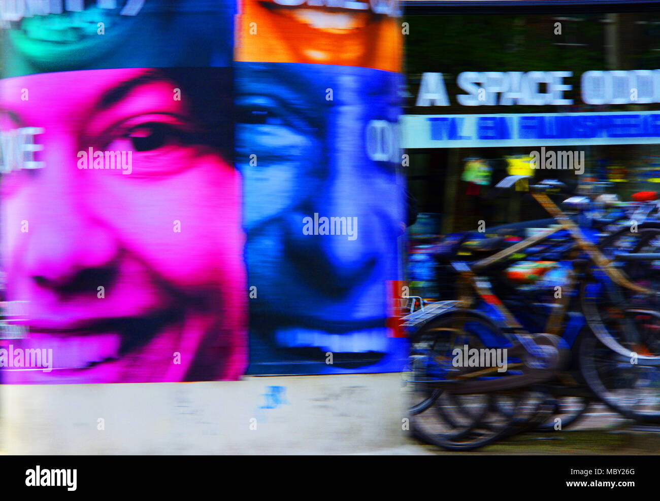 Abstract street scene depicting posters of a man and a woman laughing and smiling adjusted to crimson and blue for impact, Amsterdam, the Netherlands Stock Photo