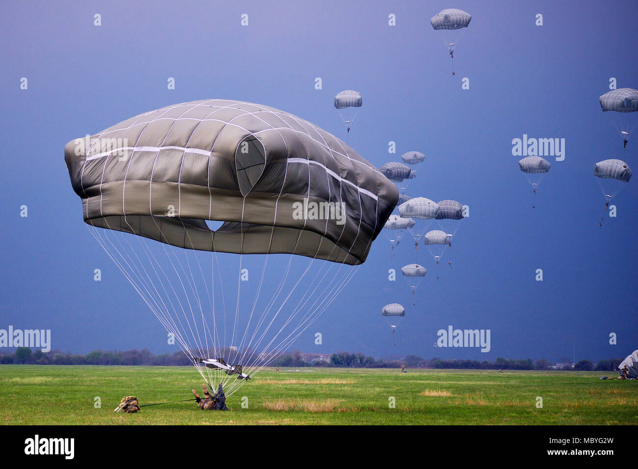 A U.S. Army Paratrooper assigned to the 173rd Airborne Brigade, Italian Army Paratroopers assigned to Folgore Brigade and Poland Paratroopers prepares to land after exiting a U.S. Air Force C-130 Hercules aircraft at Juliet Drope Zone in Pordenone, April 10, 2018. The 173rd Airborne Brigade is the U.S. Army Contingency Response Force in Europe, capable of projecting ready forces anywhere in the U.S. European, Africa or Central Commands' areas of responsibility. (U.S. Army photo by Paolo Bovo) Stock Photo