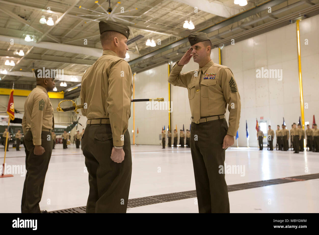 U.S. Marine Corps Sgt. Maj. Sean Cox, right, incoming sergeant major, Marine Helicopter Squadron One (HMX-1), salutes Col. Garrett Hoffman, center, commanding officer, HMX-1, during a relief and appointment ceremony at HMX-1, Marine Corps Base Quantico, Va., March 23, 2018. Sgt. Maj. Devon Lee, outgoing sergeant major, relinquished command to Cox. Stock Photo