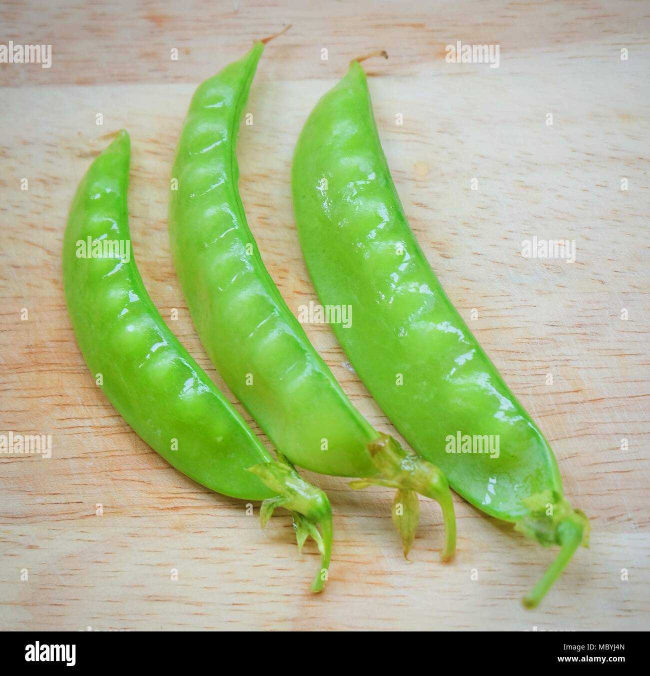 Vegetable, Fresh Green Peas Pods on Cutting Board, High in Vitamin K, B, C and A. Stock Photo