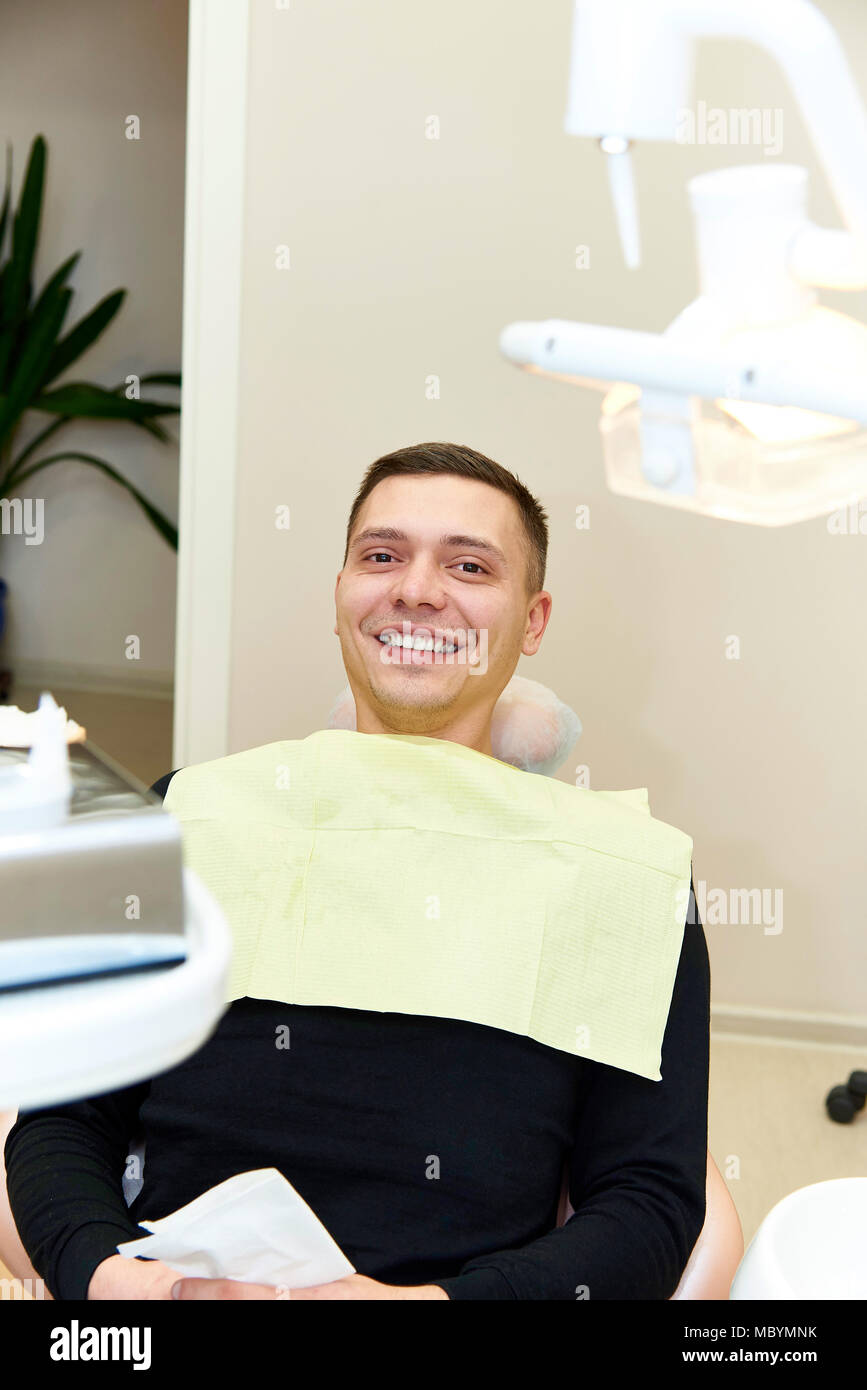 Happy young man sitting in dental chair Stock Photo
