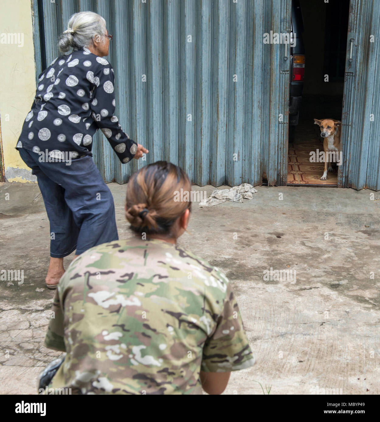 Indonesia (April 4, 2018) Army Spc. Toni Weaver (center), from Castroville, Texas, and a local resident attempt to retrieve a stray dog during a rabies vaccination event.  Service members assigned to Military Sealift Command hospital ship USNS Mercy (T-AH 19) are currently deployed in support of Pacific Partnership 2018 (PP18).  PP18’s mission is to work collectively with host and partner nations to enhance regional interoperability and disaster response capabilities, increase stability and security in the region, and foster new and enduring friendships across the Indo-Pacific Region. Pacific  Stock Photo