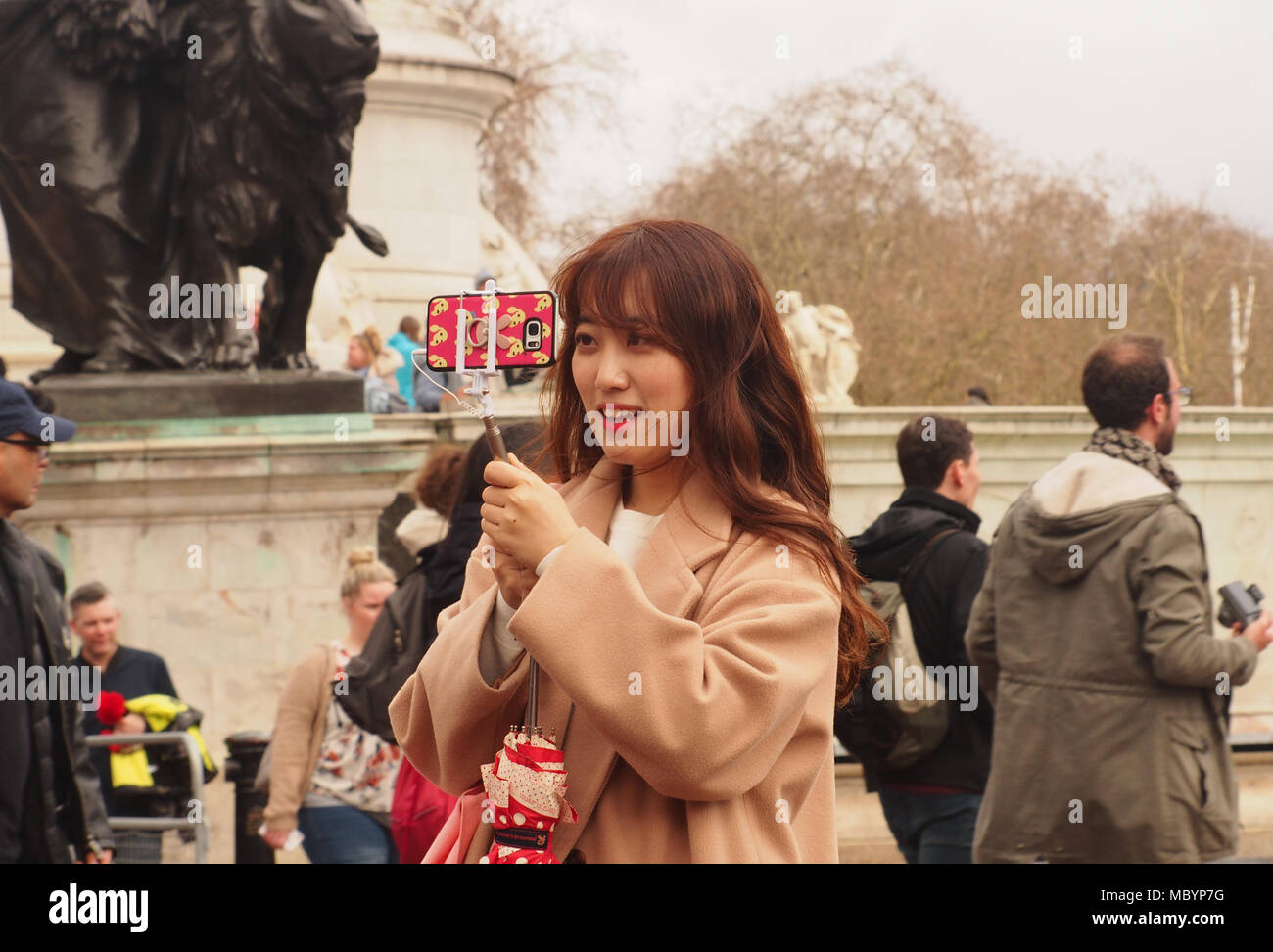 A young woman taking a selfie on her smartphone in the area in front of Buckingham Palace, London Stock Photo