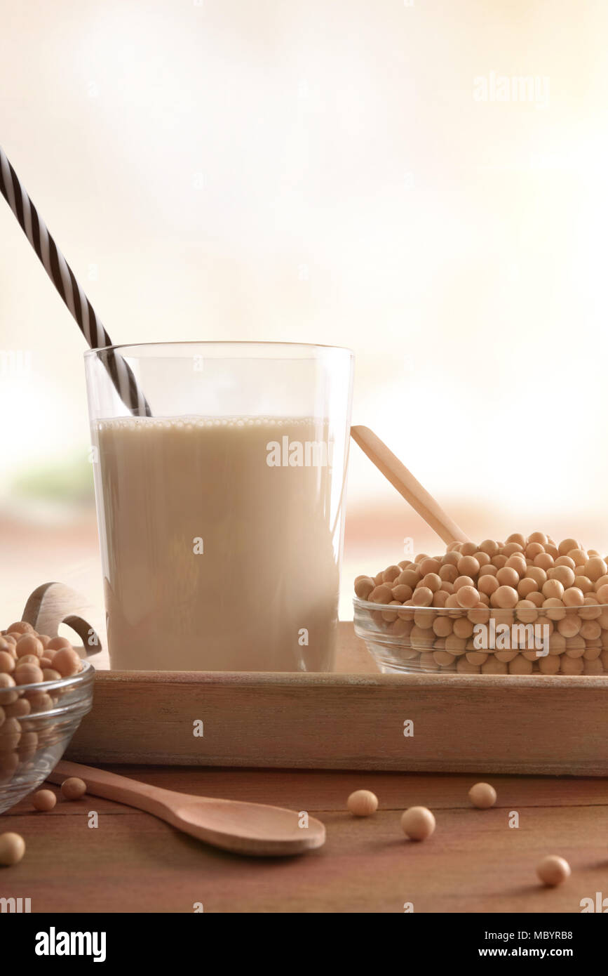 Reptientes with soy milk and grains on a wooden table in white kitchen background. Alternative milk concept. Front view. Vertical composition Stock Photo