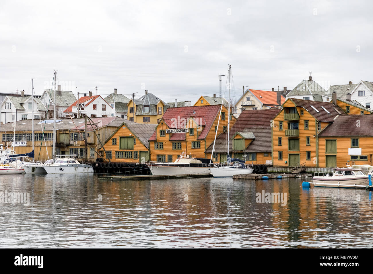 Haugesund, Norway - January 9, 2018: Old wooden houses on the island Risoy, boats and fishing industry buildings. Sild-eksport meaning Herring-export in norwegian. Stock Photo