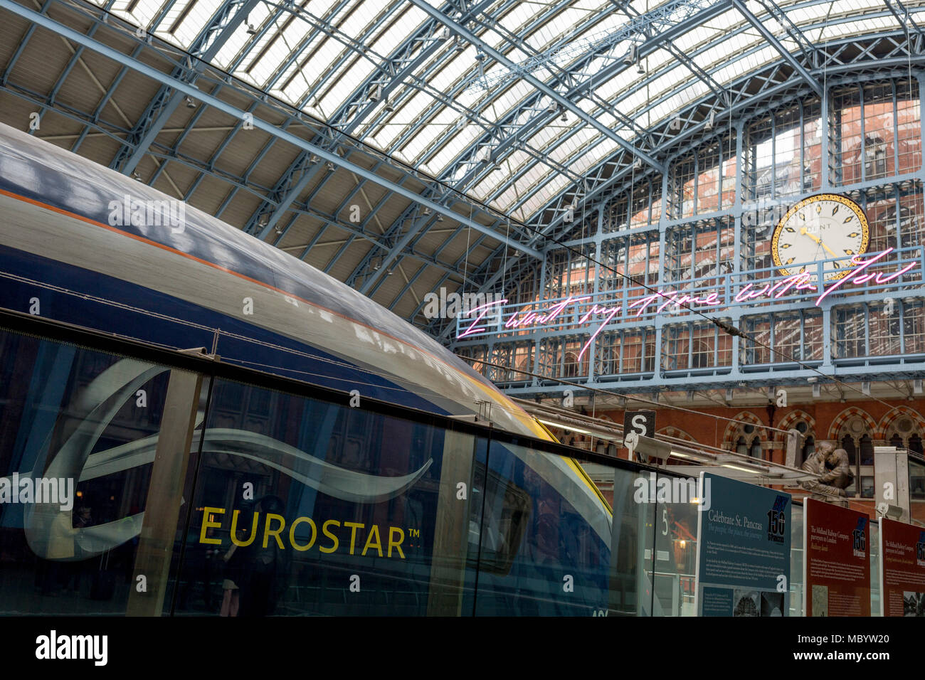 A Eurostar train and the new artwork entitled 'I Want My Time With You' by British (Britpop) artist Tracy Emin hangs over the main concourse at St. Pancras Station, on 10th April 2018, in London, England. In the sixth year of the Terrace Wires Commission - and in celebration of the 150th anniversary of St Pancras International and the 250th anniversary of the Royal Academy of Arts, at one of London's mainline station, the London hub for Eurostar - the 20 metre-long greeting to commuters reads 'I Want My Time With You' and Emin thinks that arriving by train and being met by a lover as they put  Stock Photo