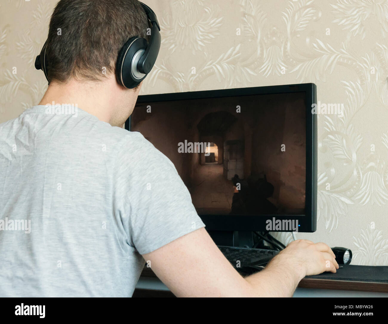 Man in headphones playing computer shooter game. Stock Photo