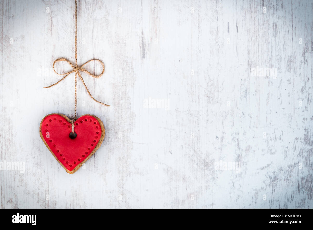 Valentines day concept. Heart shaped cookie tied with hemp bow over white wood rustic background. Stock Photo
