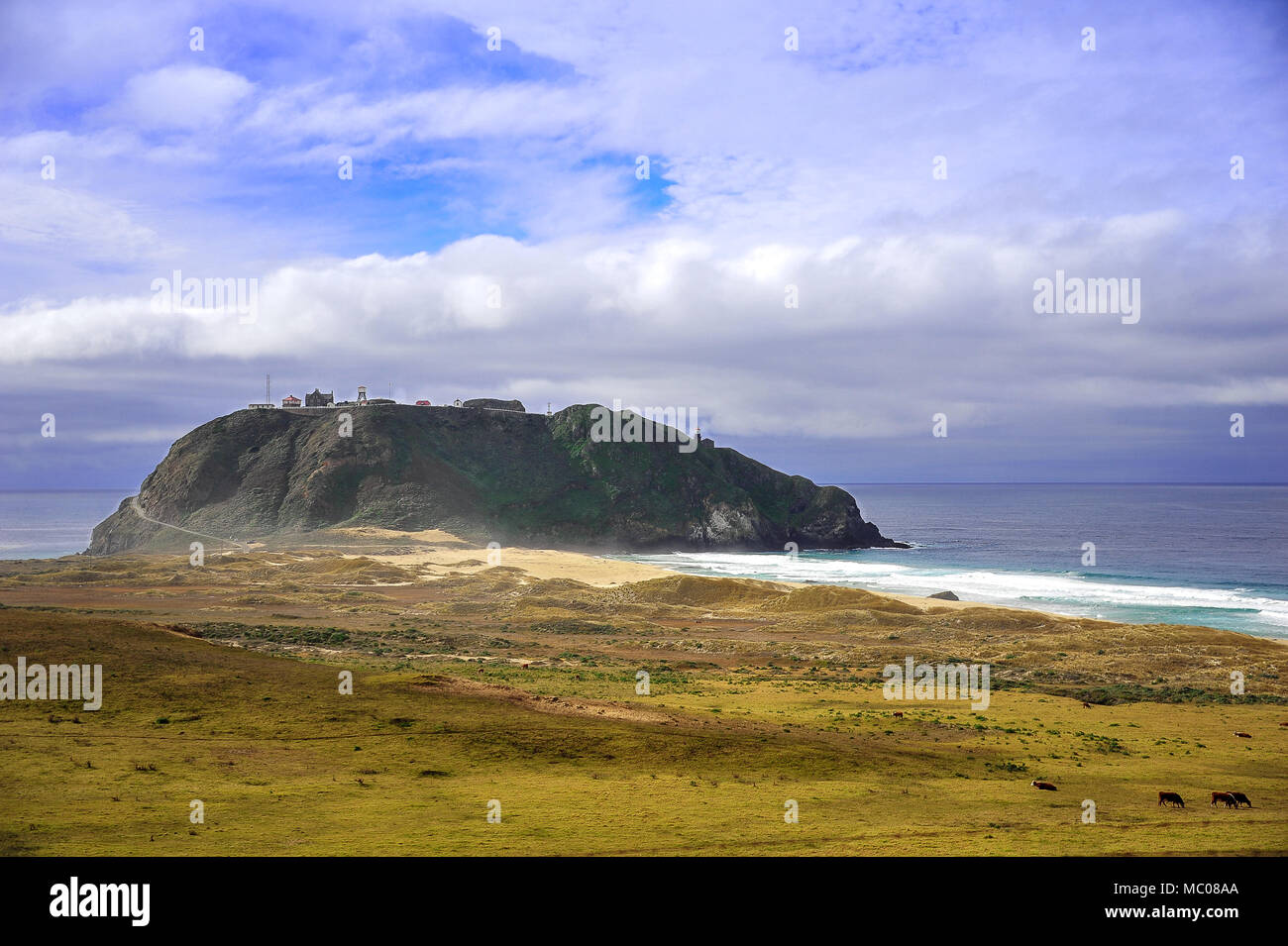 Picturesque scene of Point Sur Lighthouse from Cabrillo highway with green, grassy foreground, turquoise seas  and cloudy sky Stock Photo