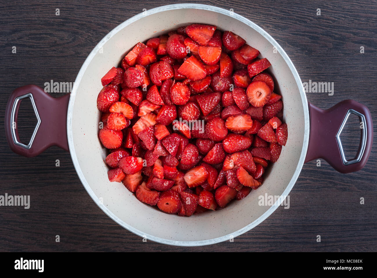 Top view of a pot with fresh strawberries cut in pieces, prepared for a strawberry jam cooking. Stock Photo