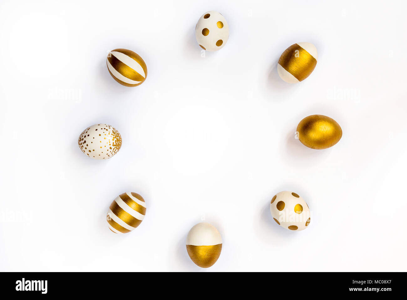 Top view of easter eggs colored with golden paint in differen patterns arranged in circle. Various striped and dotted designs. White background. Copy  Stock Photo