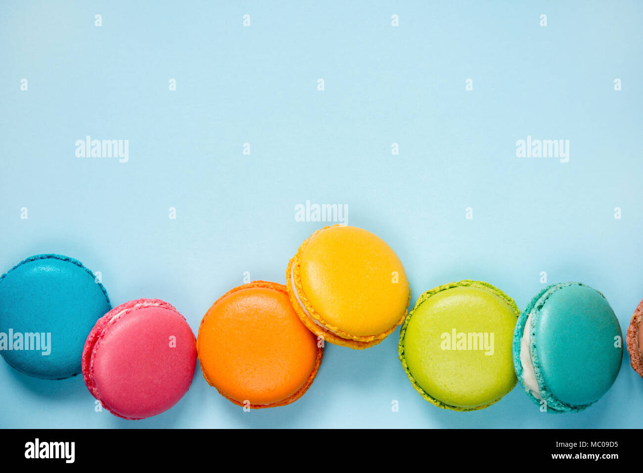 Colorful macaroons arranged over blue background. Copy space. Stock Photo