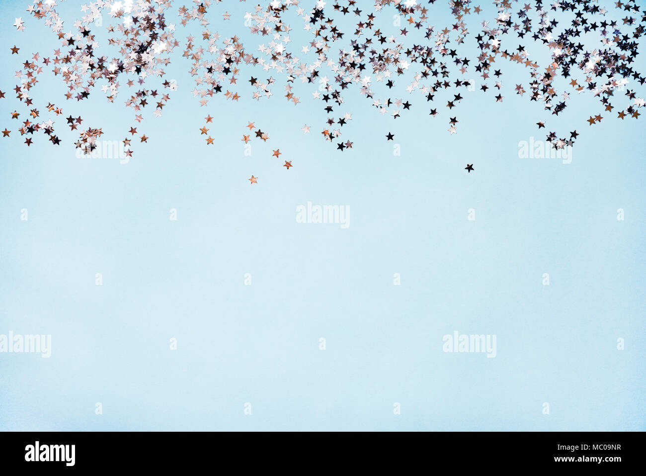 Star shaped silver sequins over blue background. Copy space. Stock Photo