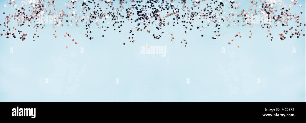 Star shaped silver sequins over blue background banner. Copy space. Stock Photo
