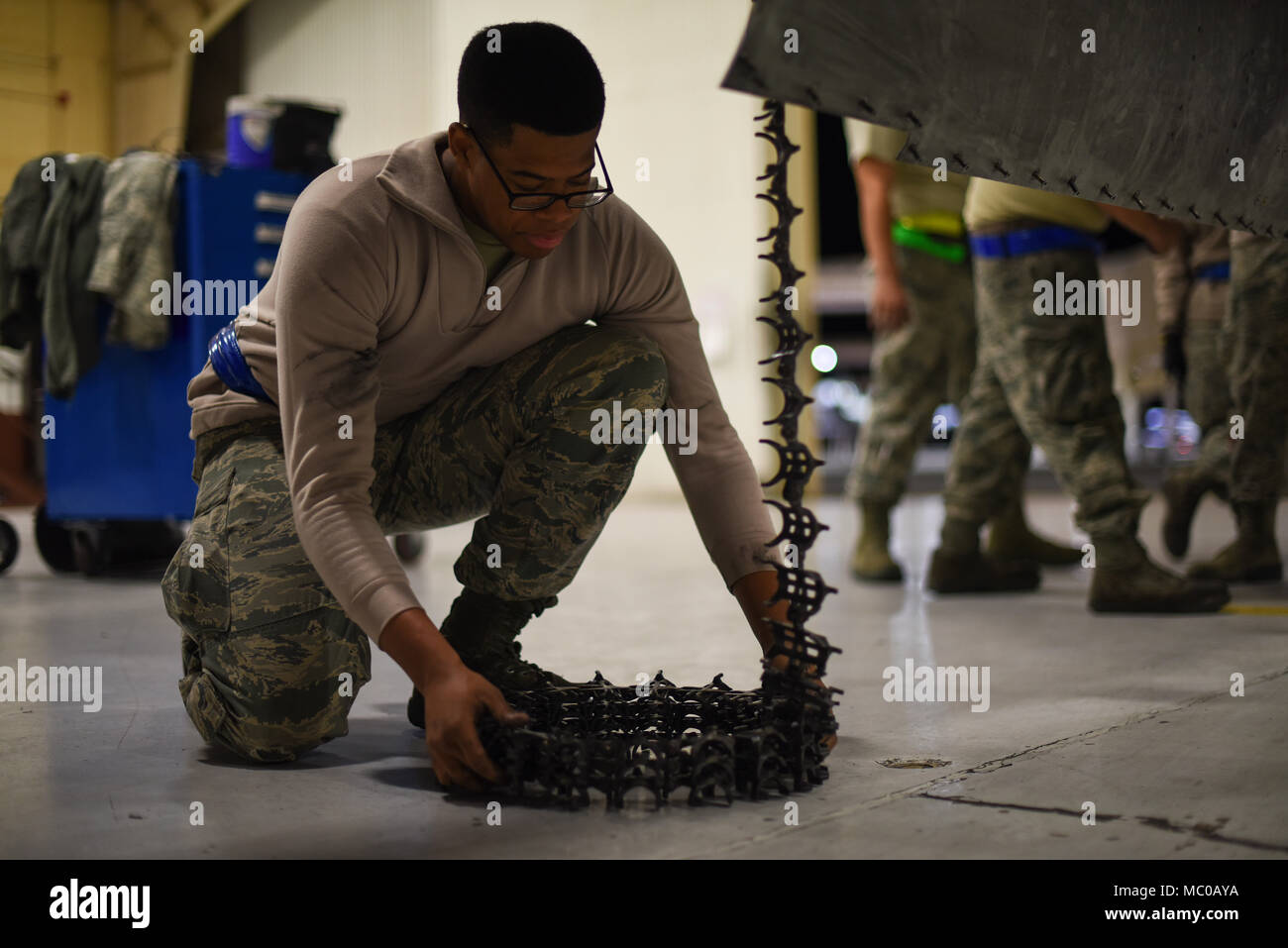 U.S. Air Force Airman 1st Class Devin Mayweather, 354th Aircraft Maintenance Unit weapons load crew member, coils a flexible magazine from an A-10C Thunderbolt II at Davis-Monthan Air Force Base, Ariz., Jan. 8, 2018. The magazine must be detached prior to the removal of the A-10’s GAU-8 Avenger 30 mm cannon. (U.S. Air Force photo by Airman 1st Class Frankie D. Moore) Stock Photo