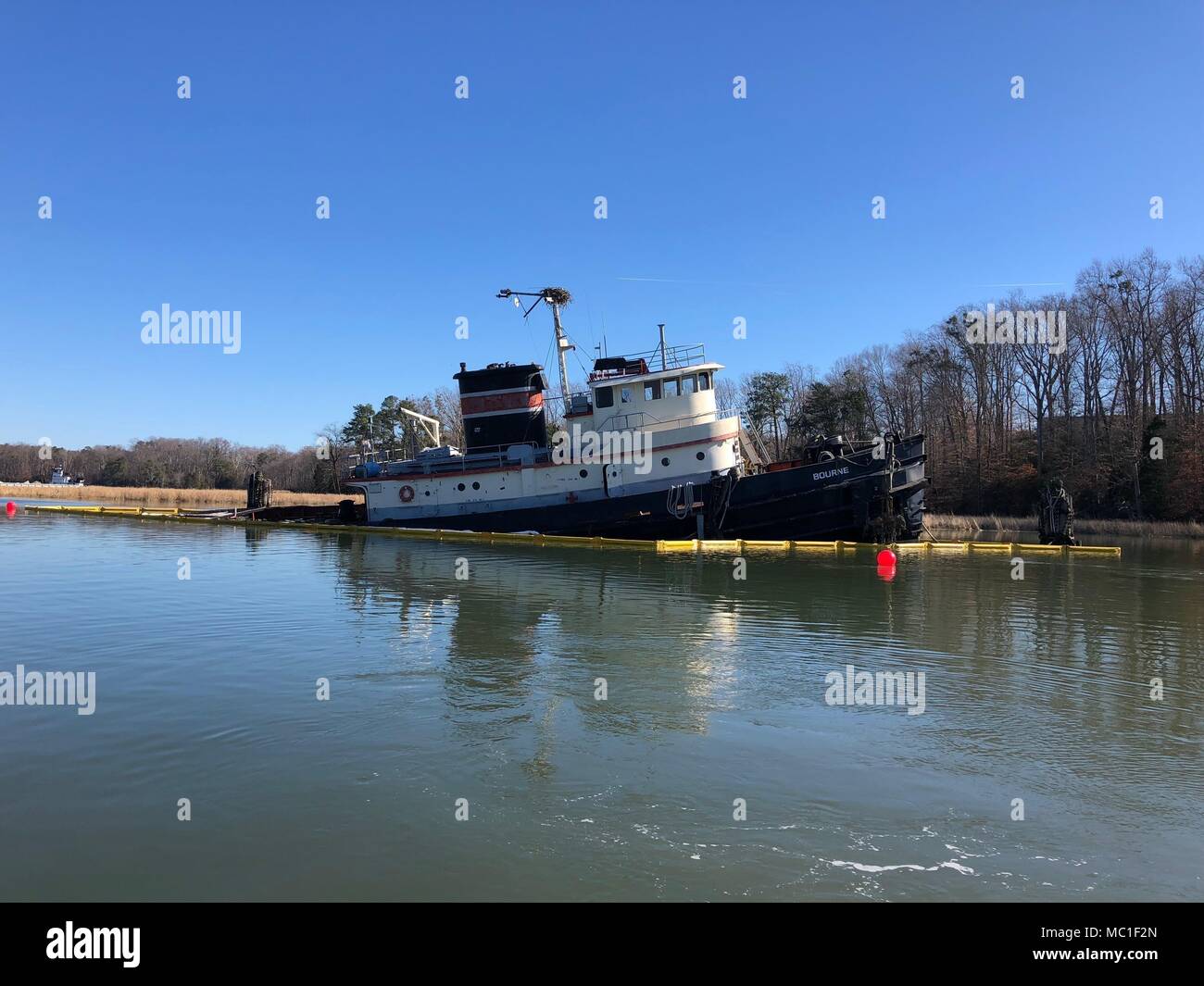 The tugboat Bourne sits partially submerged on Skiffes Creek in Newport News, Virginia, Jan. 22, 2018. The boat discharged approximately 5 to 10 gallons of motor oil, which was contained by the Coast Guard, the Newport News Hazardous Materials Team and the Virginia Department of Emergency Management with absorbent pads and a floating barrier. (U.S. Coast Guard photo by Lt. j.g. Stasia Ellis) Stock Photo