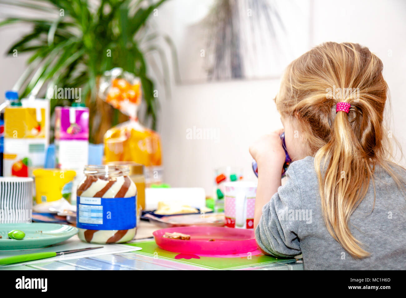 Cute little girl sitting and drinking at the breakfast table. Stock Photo