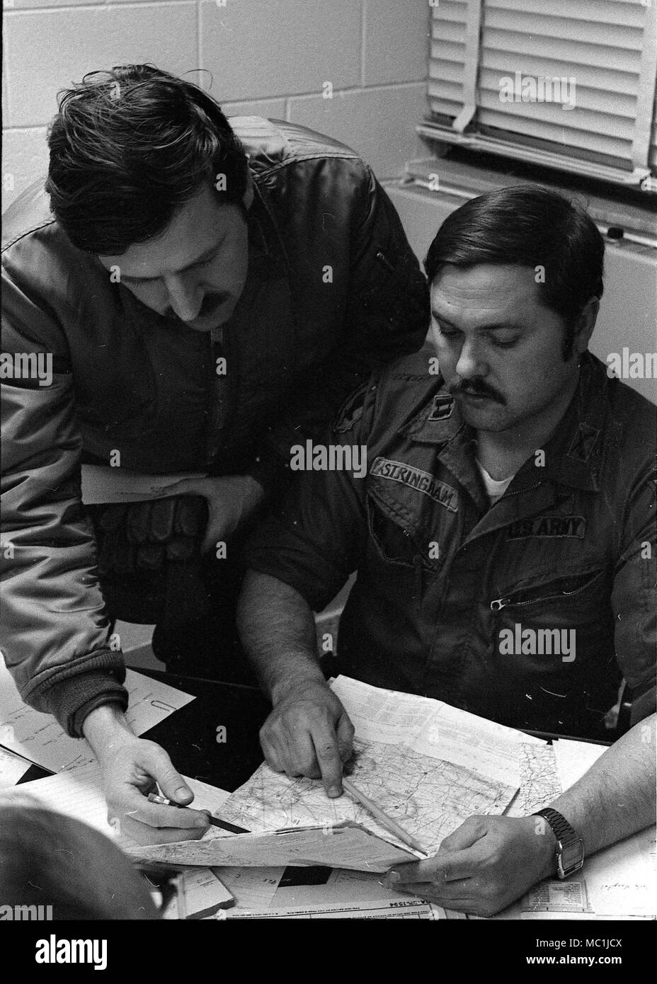 Capt. Lawrence Hays (from left), Troop N, 107th Armored Cavalry, and Capt. Roy Stringham, 54th Support Center, plan flight operations from the Toledo Air National Guard base during the “Blizzard of ’78.” Ohio National Guard helicopter crews worked around the clock on medevac, rescue and resupply missions, averaging more than 200 flights a day during the peak period. (Ohio Army National Guard Historical Collections) Stock Photo