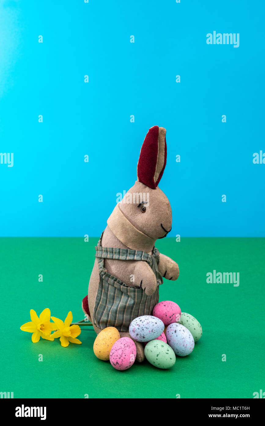 Vintage toy rabbit, bunny, with a pile of chocolate easter eggs. Stock Photo