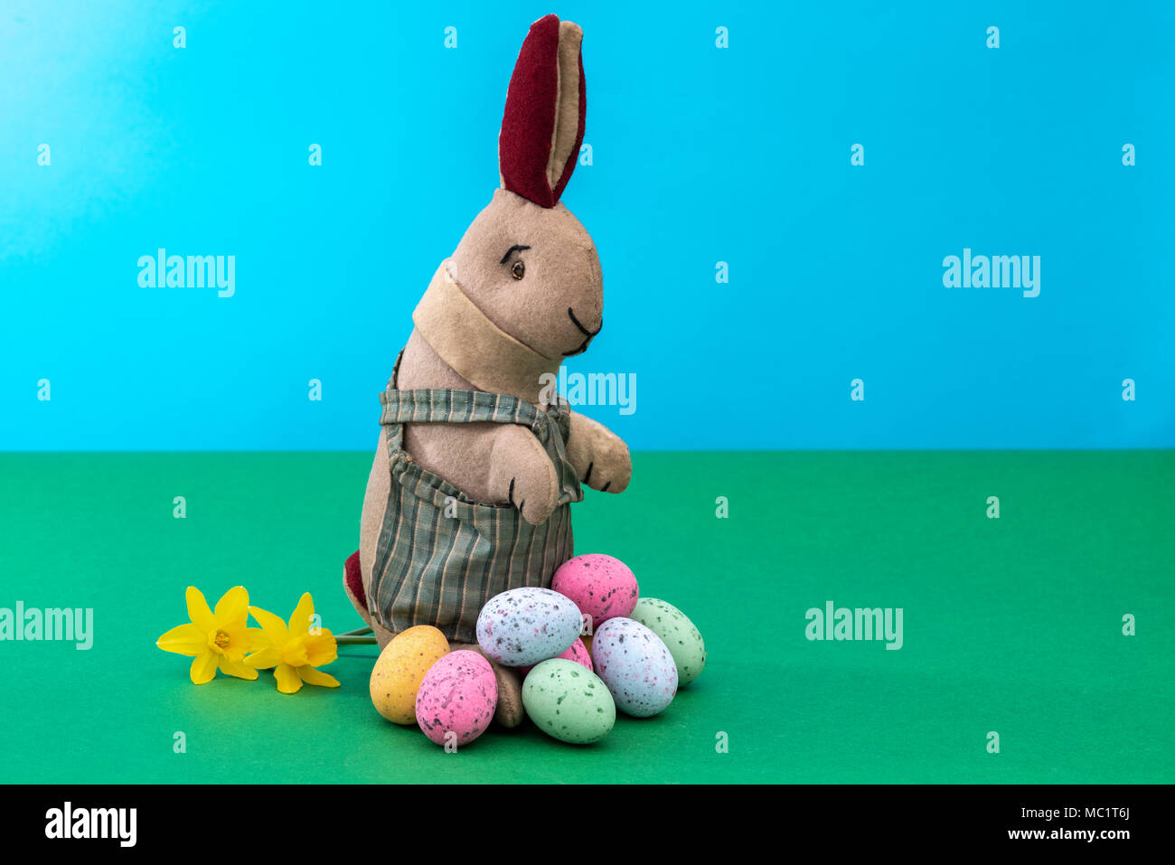 Vintage toy rabbit, bunny, with a pile of chocolate easter eggs. Stock Photo