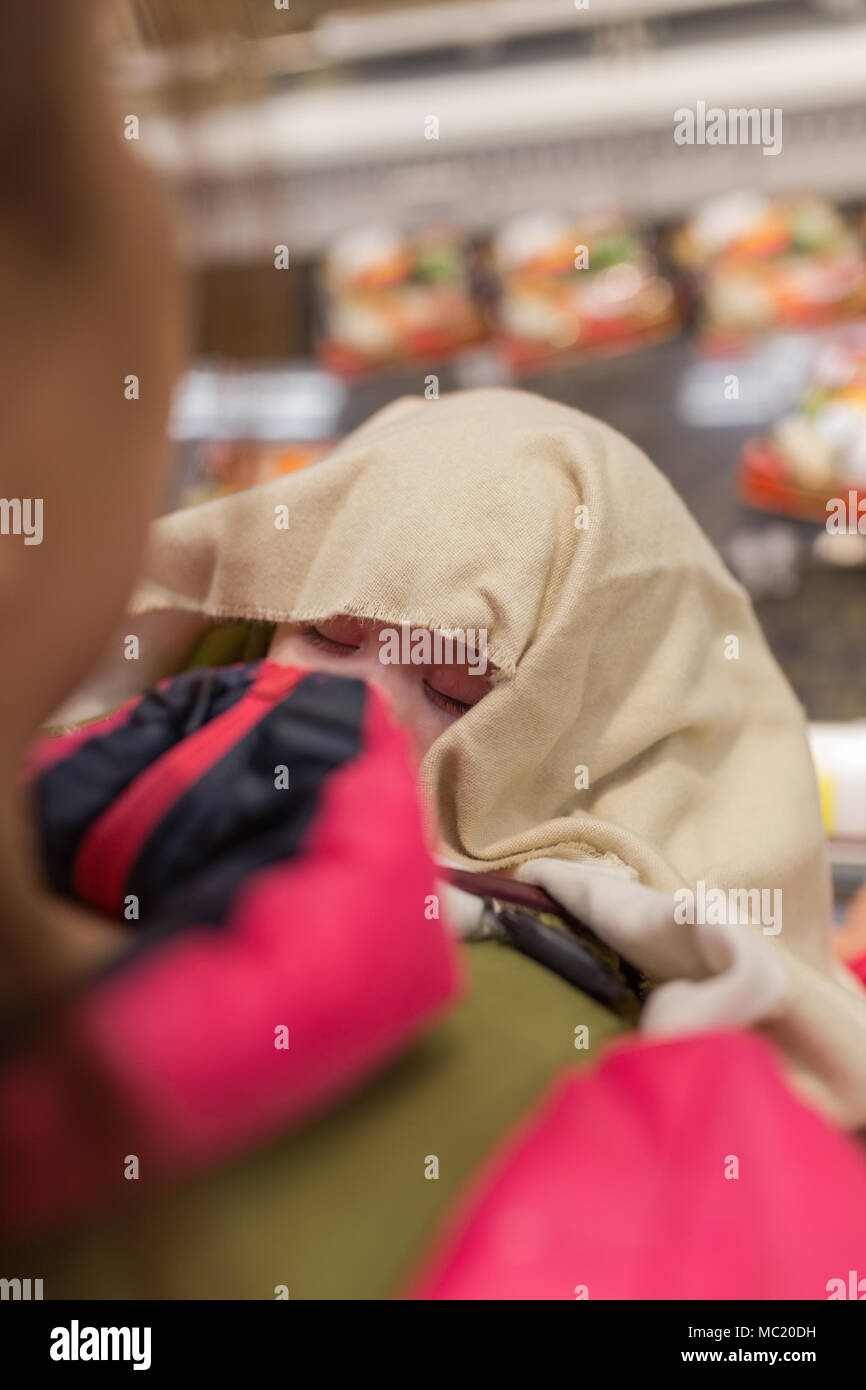Baby sleeping in baby carrier while mother shops Stock Photo Alamy