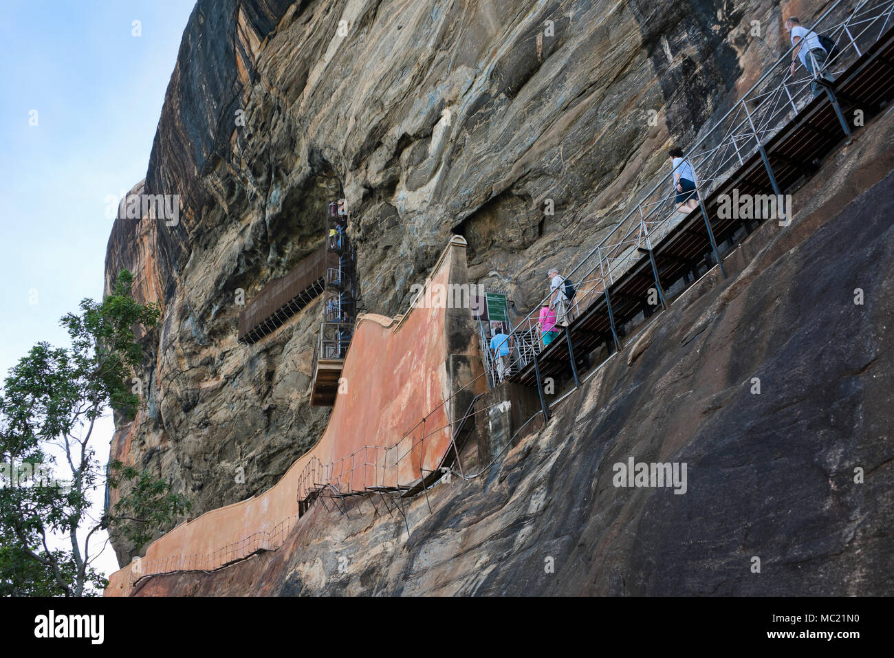 Horizontal view of tourists on the pathway clinging to the side of the cliff at Sigiriya or Lions Rock in Sri Lanka. Stock Photo