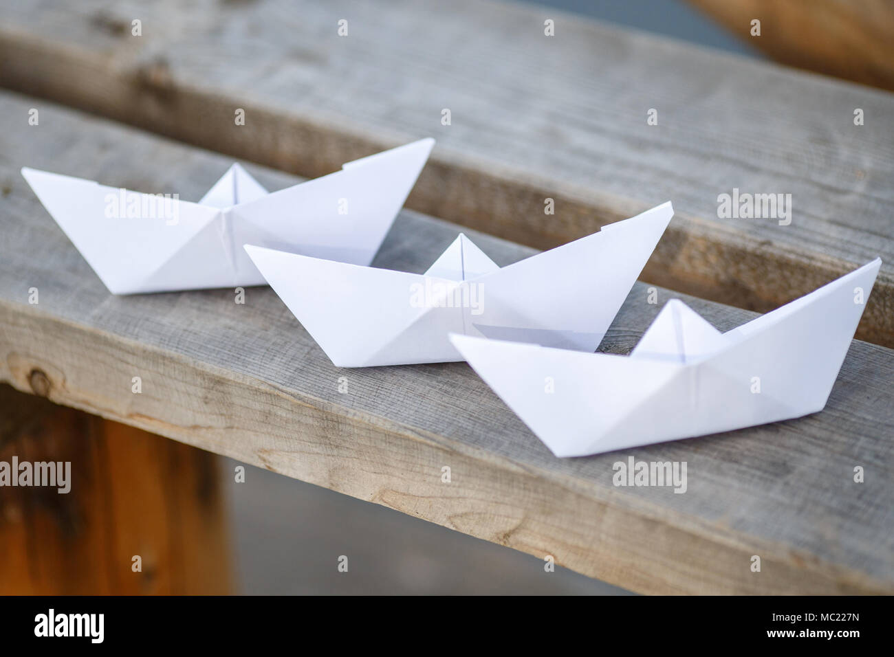 Three white paper boats on wooden bench, closeup Stock Photo